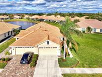 Aerial view of a beautiful home community with lush landscaping and a lake at 4980 Whispering Oaks Dr, North Port, FL 34287