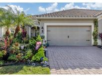 Landscaped front yard with paver driveway and two-car garage at 1195 Collier Pl, Venice, FL 34293