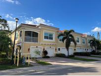 Tan colored building with garages and balconies. Lush landscaping and palm trees at 128 Navigation Cir # 103, Osprey, FL 34229