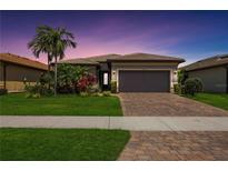 Beautiful single-story home features a well-manicured lawn and a brick driveway leading to an attached two-car garage at 13510 Esposito St, Venice, FL 34293