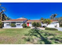 A charming mid-century ranch home with a red door, gray and white exterior, and lush lawn at 1640 Lemon Bay Dr, Venice, FL 34293