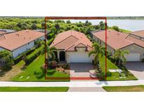 Single-story home with tile roof, two-car garage, and landscaped yard at 24076 Spartina Dr, Venice, FL 34293