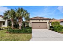 Single-story home with brown garage door and landscaping at 287 Cassano Dr, Nokomis, FL 34275