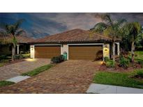Two-car garage with paver driveway and lush landscaping at 12313 Amica Loop, Venice, FL 34293