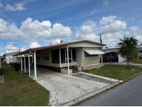 Tan single-wide manufactured home with carport and mature landscaping at 611 50Th Avenue W Dr, Bradenton, FL 34207