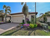 Charming home with a two-car garage, terracotta roof, lush landscaping, and brick paver driveway at 125 Soliera St, Nokomis, FL 34275