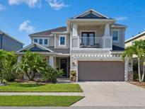 Two-story home with neutral paint, balcony, manicured lawn and tropical landscaping at 5930 Anise Dr, Sarasota, FL 34238