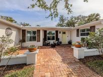 Charming home entrance with brick walkway, decorative flower pots, and inviting outdoor seating area at 705 Armada N Rd, Venice, FL 34285