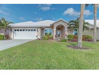 Charming single-story home with a white roof, arched entry, and lush landscaping at 1558 Belfry Dr, Venice, FL 34292