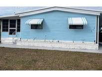 Charming blue home featuring awnings and well-maintained front yard with garden feature at 356 Longwood Dr, Venice, FL 34285
