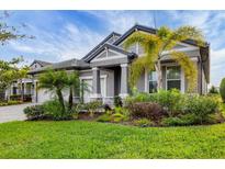 Beautiful gray home showcasing lush landscaping and inviting architectural design at 19807 Bridgetown Loop, Venice, FL 34293