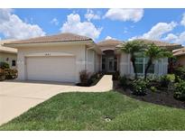 Charming single-story home with manicured lawn, lush landscaping, and a well-maintained tile roof at 651 Lakescene Dr, Venice, FL 34293