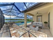 A beautiful screened patio features a dining area, cozy seating around a fire pit, and a stunning lake and pool view at 9895 Wingood Dr, Venice, FL 34292