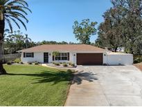 Charming single-story home with a well-manicured lawn, mature palm trees, and a driveway leading to an attached garage at 809 Garland Ave, Nokomis, FL 34275