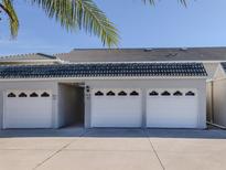 A row of garages with white doors and a grey tiled roof, under a sunny, blue sky at 936 Capri Isles Blvd # 102, Venice, FL 34292