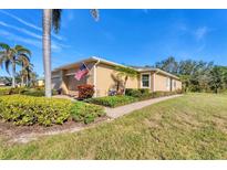 A charming home with a well-manicured lawn, lush landscaping, and a quaint walkway, with a prominent American flag display at 13542 Abercrombie Dr, Englewood, FL 34223