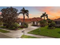 Charming single-story home featuring a red tile roof, lush landscaping, and a welcoming driveway at 133 Treviso Ct, North Venice, FL 34275