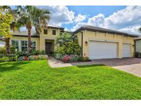 Charming yellow house with a well-manicured lawn and lush landscaping at 19832 Bridgetown Loop, Venice, FL 34293