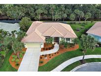 Beautifully landscaped home featuring a clay tile roof, mature palms, and circular driveway at 408 Otter Creek Dr, Venice, FL 34292