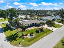 Landscaped front yard with tropical plants, lush green grass and mature trees under a sunny blue sky at 225 Randolph Rd, Venice, FL 34293