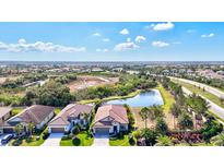 Stunning aerial view of home with tile roof situated on a lush lot with a pond view and mature landscaping at 351 Carlino Dr, Nokomis, FL 34275