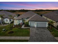 Stunning exterior view of home, showcasing a brick driveway, manicured lawn, and a two-car garage at 18135 Home Run Dr, Venice, FL 34293