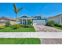 Charming, light blue single-Gathering home featuring a well-manicured lawn and paver driveway at 20420 Symphony Pl, Venice, FL 34293