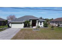 Charming single-story home featuring a well-maintained lawn, elegant front entryway, and attached two-car garage at 2115 Pan American Blvd, North Port, FL 34287