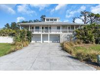 Two-story waterfront home featuring a metal roof, garage, and a charming wrap-around balcony at 2371 Scenic Dr, Venice, FL 34293