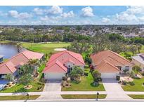 This aerial view showcases a well-maintained home with a red tile roof, manicured lawn, and beautiful landscaping at 446 Pinewood Lake Dr, Venice, FL 34285