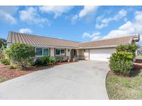 Charming single-story home featuring a tile roof, manicured landscaping, and an inviting driveway leading to a two-car garage at 5061 Richmond Ter, North Port, FL 34287
