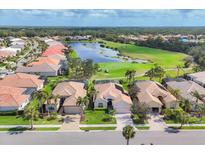 An aerial view of homes along the golf course with a lake in the community on a sunny day at 560 Misty Pine Dr, Venice, FL 34292