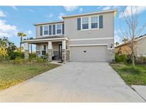 Two-story home features a neutral exterior, blue shutters, a two-car garage, and a front porch at 5767 Woodland Sage Dr, Sarasota, FL 34238