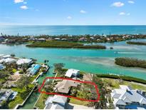 Stunning aerial view of waterfront home with boat dock and lush landscaping, nestled in a coastal community near the open ocean at 641 Bayshore Rd, Nokomis, FL 34275