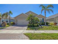Charming single-story home with a well-manicured lawn and a paver driveway leading to a two-car garage at 8969 Mondial Ct, Venice, FL 34293