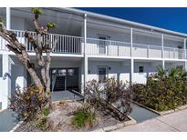 Inviting condo exterior featuring well-kept landscaping and a clean, bright facade with white railings at 902 Gibbs Rd # 181, Venice, FL 34285