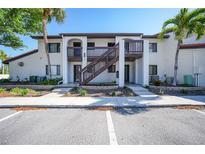 Condo exterior with stucco walls, arched entryways, wooden staircase, and beautiful landscaping at 1636 Stickney Point Rd # 36-201, Sarasota, FL 34231