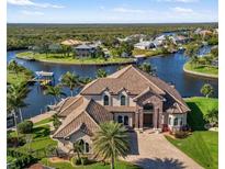 Waterfront two-story home featuring a clay tile roof, brick entryway, and lush landscaping at 19227 Palmdale Ct, Port Charlotte, FL 33948