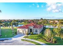 Beautiful single-story home with a red tile roof, lush landscaping, and a serene lake view at 217 Savona Way, North Venice, FL 34275