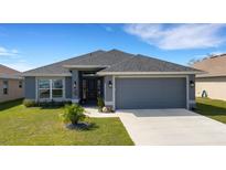 Charming single-story home showcasing a well-manicured lawn and a gray color scheme at 2572 Averland Loop, North Port, FL 34287