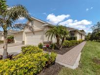 Well-maintained home exterior showcasing a manicured lawn, palm trees, and a three-car garage at 29692 Niagara Ct, Englewood, FL 34223