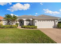 Charming single-story home featuring a well-manicured lawn, two-car garage, and elegant architectural details at 5106 Pine Shadow Ln, North Port, FL 34287