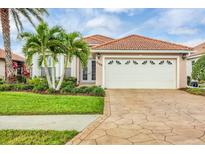 Charming single-story home featuring a terra cotta tile roof, two-car garage, and lush tropical landscaping at 5109 Pine Shadow Ln, North Port, FL 34287