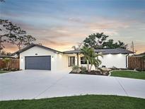 Charming single-story home with a gray garage door, a white textured facade, and tropical landscaping at 605 Cumberland Rd, Venice, FL 34293