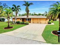 Stunning home featuring a long driveway, a two car garage, beautiful plants, and magnificent palms at 705 Cadiz Rd, Venice, FL 34285