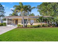 Well-maintained home with a green lawn, palm trees, and beautiful landscaping at 742 Golf Dr, Venice, FL 34285
