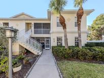 Inviting condo exterior features lush landscaping, white railings, and sunny walkway to the unit entrance at 800 Gardens Edge Dr # 814, Venice, FL 34285
