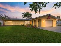 Charming one-story yellow home with an attached garage, well-manicured lawn, and lush tropical landscaping at 929 The Rialto, Venice, FL 34285