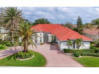 Stunning single-Gathering home with a beautiful red roof, well-manicured lawn, and circular brick driveway at 945 Chickadee Dr, Venice, FL 34285
