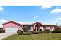Charming pink home with a well-manicured lawn and white trim against a blue sky at 111 2Nd St, Nokomis, FL 34275